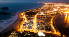 View of a beachside town at night lit up by lights on streets and in buildings. 