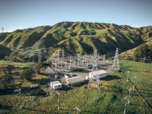 Image of a substation situated below hills and on lush green fields